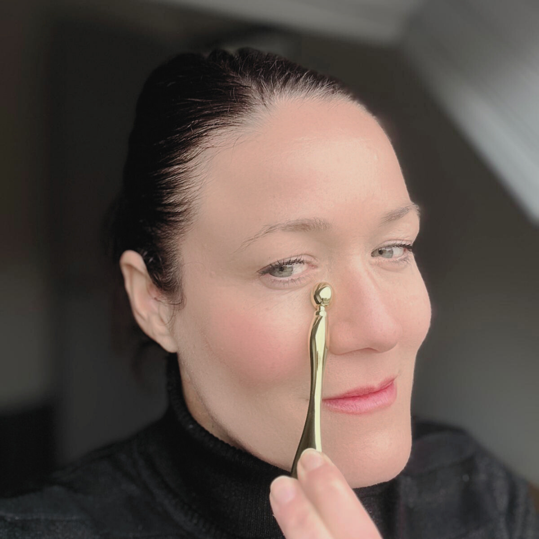 Femme mature utilisant le masseur oculaire Éclat d’Or pour lisser le contour des yeux et stimuler la microcirculation, dans une ambiance douce et lumineuse Belle après 40 ans.